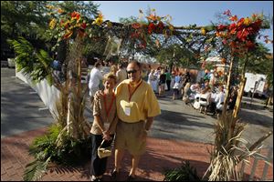 Kelly and Tim Colman pose at the decorative entrance to the VIP garden at the Party in the Parking Lot for the Boys and Girls Clubs at
the Toledo Club.