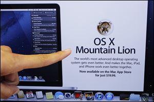A customer looks at the new OS X Mountain Lion operating system at an Apple store in Palo Alto, Calif.