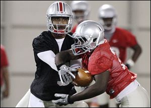 Ohio State quarterback Braxton Miller hands the ball off to running back Bri'onte Dunn during the first day of their spring NCAA college football practice.
