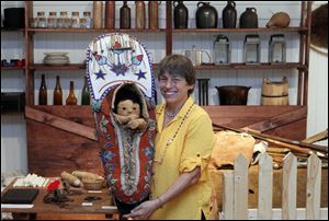 Chris Kull displays a papoose from the 1840s that is on display at the museum in downtown Monroe.