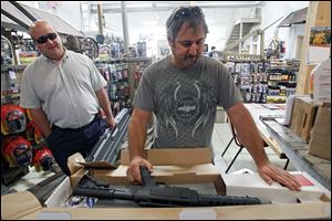 Brad Bucholz of Defiance displays the 22-caliber rifle he purchased at Cleland's Outdoor World near Swanton. Looking on is Scott Olson, a fellow gun owner who was helping  Mr. Bucholz pick up his purchases Friday.