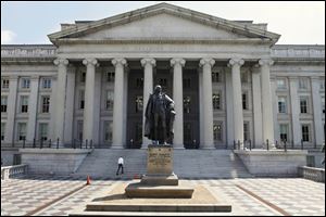 A statue of former Treasury Secretary Albert Gallatin stands guard outside the Treasury Building in Washington. The rating agency Standard & Poors stunned the world a year ago by stripping the U.S. government of its prized AAA bond rating. A year later, S&Ps historic move looks like a non-event. Long-term interest rates are sharply lower, the Dow Jones industrial average has reversed course and is now up more than 1,600 points. The dollar has rallied, and gold prices are down from where they were when S&P lowered the boom.