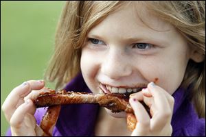 Zoe Edwards, 9, of Maumee  sinks her teeth into a rib at the 29th annual Northwest Ohio Rib-Off  at the Lucas County Fairgrounds.  