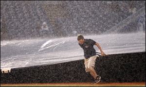 The grounds crew brings out the tarp at the start of a fourth-inning rain delay Friday night at Fifth Third Field.  That game will resume today at 5:30 p.m. with a seven-inning game to follow.