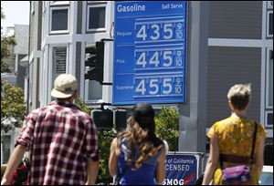 A group of pedestrians walk toward a Chevron gas station price board Friday in San Francisco. Gasoline prices in the United States rose over the past two weeks, driven partly by supply disruptions and a drought-induced rise in ethanol prices, a widely followed survey showed on Sunday.