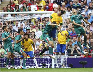 Mexico's Hiram Mier (4) and Jorge Enriquez (14) jump for the ball against Brazil's Leandro Santos during Saturday's gold medal match.