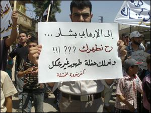 A Syrian man holds a poster with Arabic writing that reads, 