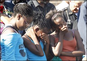 Daijha Murphy, 11, Diamond Brown, 12, and Carmanetta Wilson, 12, pray during a prayer vigil for two children who were recently shot in a Moody Manor apartment. Brown lives in the Moody Manor apartments.