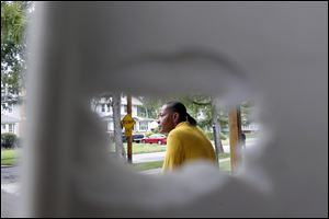 Anna Branch sits on the front porch of her central city home. She can be seen here through a bullet hole in a plastic chair.