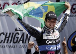 Nelson Piquet Jr., holds the Brazilian flag while celebrating in victory lane after winning the NASCAR Camping World Truck series VFW 200 at Michigan International Speedway.