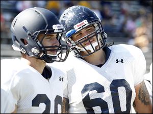 A.J. Lindeman, right, talks to a teammate in practice. The former walk-on will likely start on the offensive line.