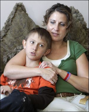 Donna Hisey holds her son, Tanner, in their home in Clyde. Tanner  says he gets frightened by aches and pains, afraid that they are signs that his cancer has returned. A recently released report says investigation of Clyde-area sites found no contamination.