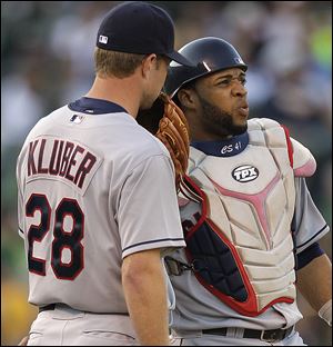 Cleveland Indians' Corey Kluber, left, speaks with catcher Carlos Santana in the third inning of a baseball game  against the Oakland Athletics on Saturday, Aug. 18, 2012, in Oakland, Calif.