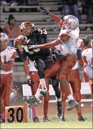Rogers defensive back Joshua Taliaferro leaps to intercept a pass intended for Bowsher's Dashan White. Taliaferro was also third in the City League last season with 422 receiving yards.
