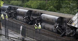 Officials stand near part of a CSX freight train that derailed overnight in Ellicott City, Md.