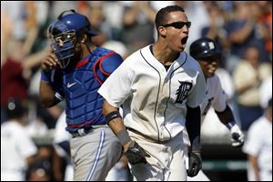 Detroit Tigers' Quentin Berry celebrates scoring the winning run on a single by Alex Avila as Toronto Blue Jays catcher Yorvit Torrealba kneels after trying to make the tag in the 11th inning of a baseball game on Thursday. 