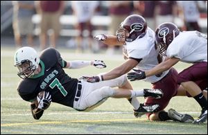 Ottawa Hills High School player Cole Ferguson, 7, is hit by Genoa High School player David Nutter, 25, during the first quarter at Ottawa Hills on Friday.