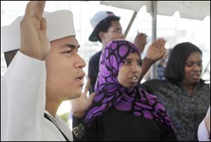 Petty Officer 3rd Class Trevor Viguilla, left, formerly of the Philippines, Muna Ahmed Abdi, formerly of Somalia, and Mathrine Mazani, formerly of Zimbabwe, become new citizens aboard the USS De Wert. The new citizens at Friday's ceremony were surrounded by naval officers.