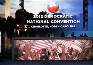 A man crosses the main stage for the convention. Preparations were still under way Saturday for the gathering, which begins Tuesday.

