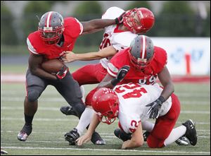 Central Catholic's Amir Edwards, left, stiff arms Bedford defender Spencer Cimerman. Edwards finished with 156 yards rushing.