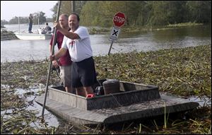 Neighbors Cisco Gonzales, front, and Josh Brockhaus head for shore after checking their homes in Braithwaite, La., where Hurricane Isaac left a soggy mess. Parts of Louisiana and Mississippi got up to 2 feet of water.