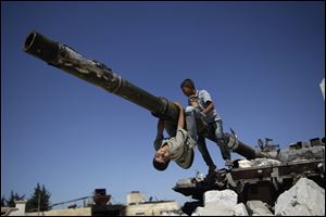 A  boy looks back while he and another boy play on a Syrian military tank, destroyed during fighting with the Rebels on Sunday in the Syrian town of Azaz, on the outskirts of Aleppo.