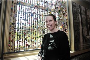 Jennifer Bandeen, the art museum's Community Gallery manager and community outreach coordinator, stands in front of one of the bead curtains in the cafe. Contributor's, who have a wide variety of ability levels, used clay, glass, wood, and other materials to make the beads.