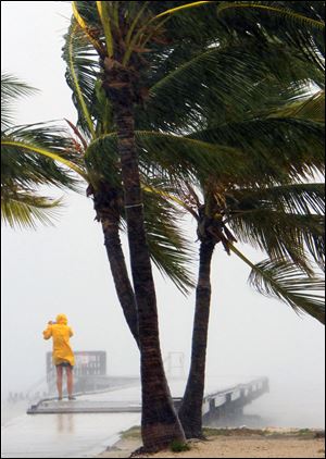 A person braves the rain at Clarence Higgs Beach in Key West, Fla., last week as Tropical Storm Isaac hits the area. More crews are returning to offshore drilling rigs and production platforms as the weather clears after Isaac.