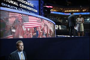 First Lady Michelle Obama appears on stage with actor Kal Penn for filming a campaign video as a Secret Service agent watches the floor where the hall is being readied for the Democrats' convention.
