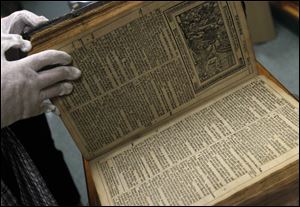 Sister Sandra Rutkowski opens a Bible printed in 1688. Several antique and rare Bibles will be on display in October's King James Bible exhibit.