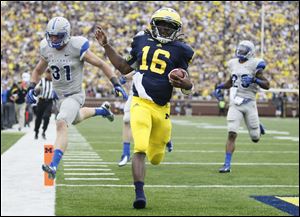 Michigan's Denard Robinson races past Air Force's Brian Lindsay, left, and Steffon Batts for a touchdown.