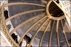 The stained-glass dome in the courthouse's main courtroom was covered by a suspended ceiling in the 1950s. In the process, holes were crudely punched for duct work and wiring to hold the ceiling.
