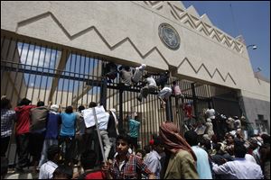 Protesters scale the main gate outside the U.S. Embassy in Sanaa, Yemen, on Thursday in anger over the release of a U.S.-made video critical of the prophet Mohammed, depicting him as being of questionable moral character.