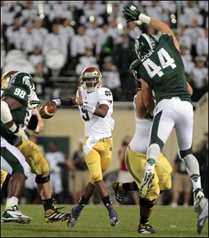 Notre Dame quarterback Everett Golson, center, looks to pass between Michigan State's Marcus Rush (44) and Anthony Rashad White (98) during the first quarter of an NCAA college football game, Saturday.