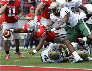 Ohio State's Braxton Miller, left, scores a touchdown against Alabama-Birmingham's Jake Genus, bottom, and Lamar Johnson (6) during the second quarter of an NCAA college football game Saturday.