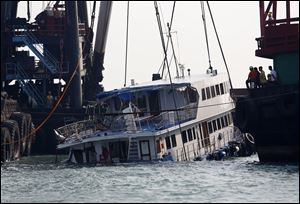 A half submerged boat is lifted by cranes today after Monday night's collision near Lamma Island, off the southwestern coast of Hong Kong Island.
