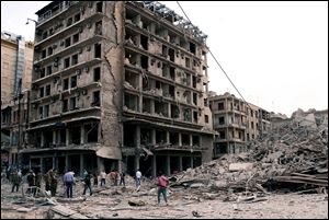 Syrian security officers gather at the scene in front of destroyed buildings where triple bombs exploded at the Saadallah al-Jabri square, in Aleppo city, Syria, Wednesday.