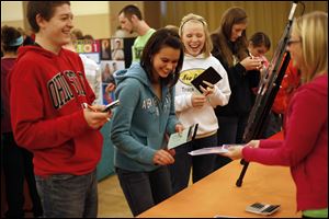 Ashley Mathias, center, a senior at New Riegel High School, laughs with her classmates Nick Wank and Abby Cassidy as she discovers that her 
