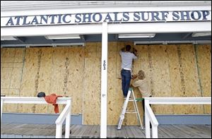Surf store workers Fletcher Birch, left, and Jay Kleman board up the windows of the store in Ocean City, Md. on Saturday as Hurricane Sandy approaches the Atlantic coast. 