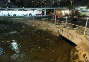 Visitors and Oahu residents watch the ocean water surge in and out of the Ala Wai Harbor  carrying various debris Saturday.