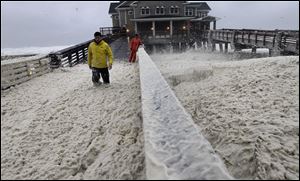 A news crew wades through sea foam blown onto Jeanette's Pier in Nags Head, N.C.
