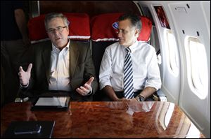 Republican presidential candidate Mitt Romney talks with former Florida Gov. Jeb Bush today as they fly on his campaign plane to Miami Fla.
