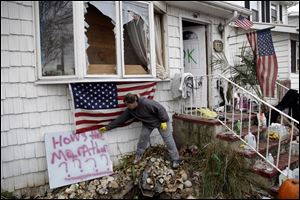 Sandra Finnegan places a sign against the marathon in front of her brother's house, which was destroyed by Storm Sandy, in Staten Island, New York on Friday.