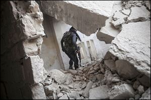 A rebel fighter walks among the debris of damaged residential buildings after several days of intense fighting between rebel fighters and the Syrian army in the Karm al-Jebel neighborhood in Aleppo, Syria. 
