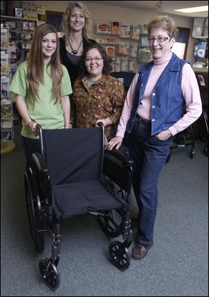 From left, Gracie Runyon, Leigh Ann Yungmann, Tri-State Medical Supply general manager, Kristen Runyon, and Cecily Rohrs surround a wheelchair similar to one headed for a man in Ukraine
