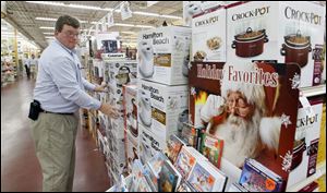 Randy Whitehead, manager at the Andersons General Store in Maumee, straightens a display. The chain plans to offer discounts on total purchases. 