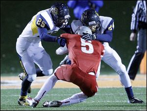 Whitmer's Austin Bly, 25, and Marcus Elliott, 24, stop Mentor's Connor Krizancic on fourth down in the second quarter. The Panthers, for the most part, had an answer for the high-powered Cardinals.