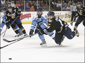 Toledo Walleye player Joey Martin, 14, shoots the puck as he's knocked down by Evansville Icemen player Matt Gens.