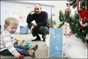 Grahame Burrow watches as his son Pierce plays with a birthday gift during their visit to ProMedica Toledo Children's Hospital. Pierce was delivered by cesarean section a year ago and immediately underwent a transfusion to replace the 90 percent of his blood that his body had lost.