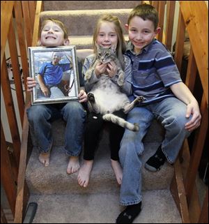 Colin and Kate Brewer, both 6, and brother Toby, 10, with their cat Leroy, deal with the sudden death of their father, Gary Brewer, in December.